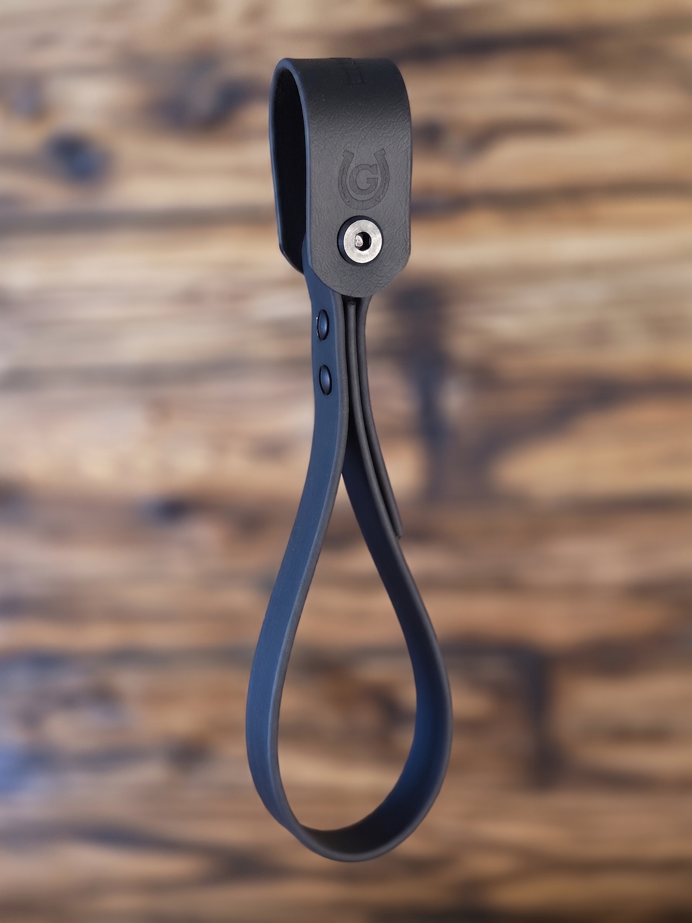 Black Biothane grab handle for truck entry assist against a blurred scorched wood background