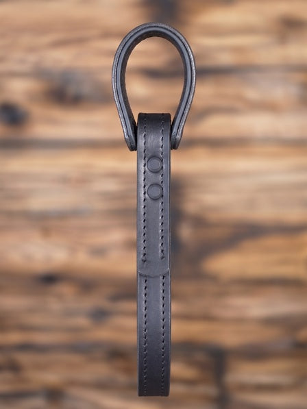 Black leather truck grab handle or vehicle entry assist strap with metal hardware against a blurred wooden background