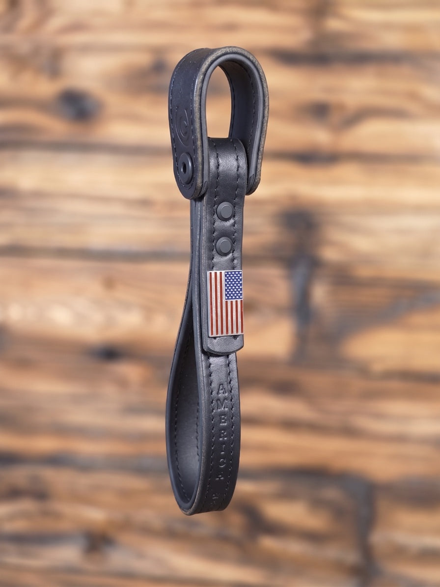 Black leather grab handle with American flag emblem on a wooden background
