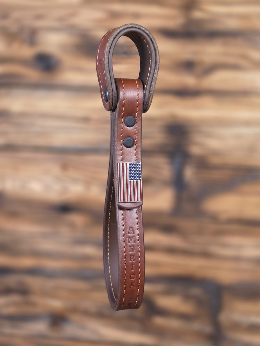 Brown leather strap with American flag emblem on a wooden background