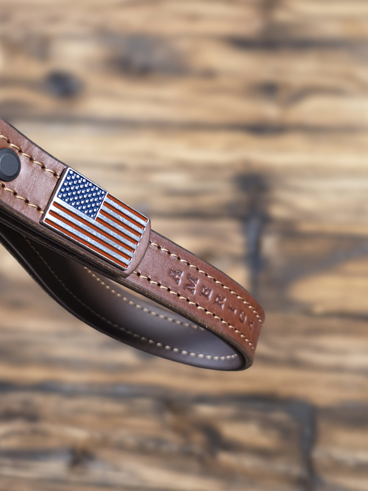 Closeup of American Flag concho on brown leather Giddyupz handle against a blurred wooden background