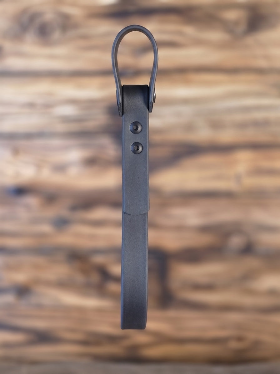 Black Biothane grab handle for home mobility assist against a blurred scorched wood background