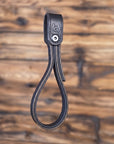 Black leather strap with a metal bolt on a wooden background