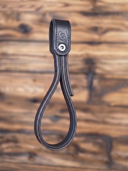 Black leather strap with a metal bolt on a wooden background