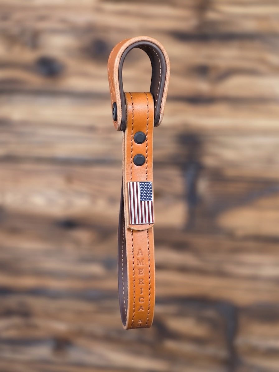 Tan leather truck entry assist grab handle with Biothane core and tan stitching, enhanced with "America 250" stamping and an American Flag concho.